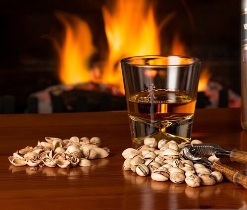 Vaso con whisky y pistachos sobre una mesa